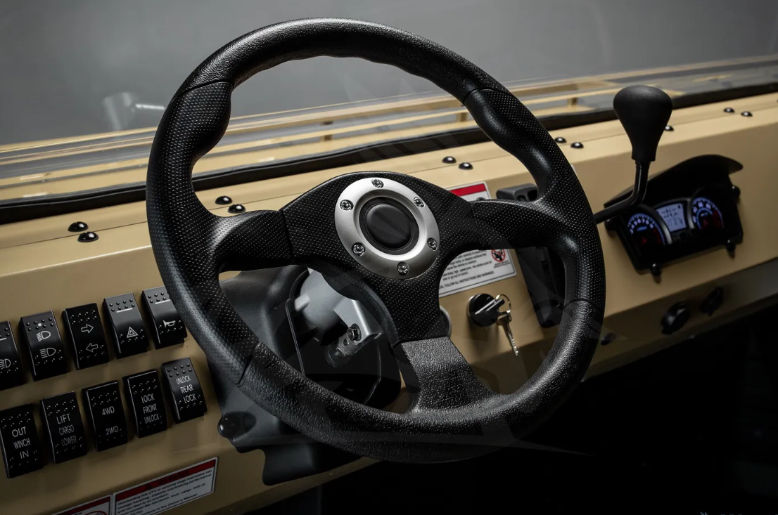 Steering wheel and beige dashboard of a heavy-duty vehicle with numerous switches in view.