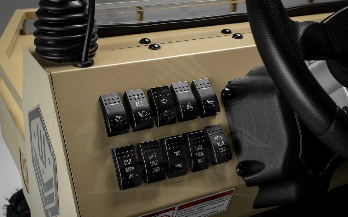 Steering wheel and beige dashboard of a heavy-duty vehicle with numerous switches in view.
